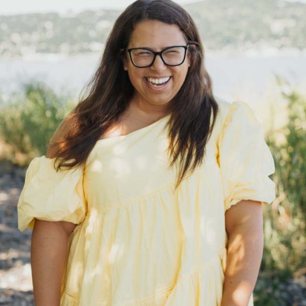Dayna smiling in a yellow dress in front of nature