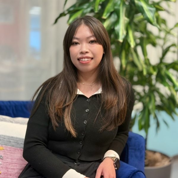 Sofia smiling at the camera with a green tree in the background